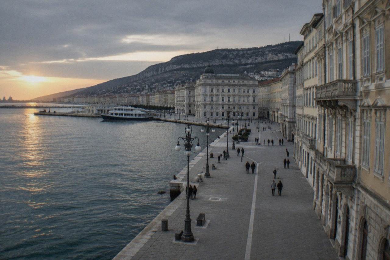 The seafront square of Trieste at golden hour with the sea on one side and ornate facades on the other