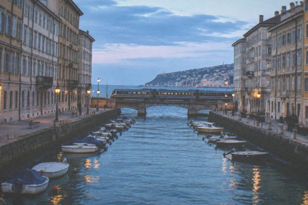A train crossing a long causeway over open water toward a distant island city