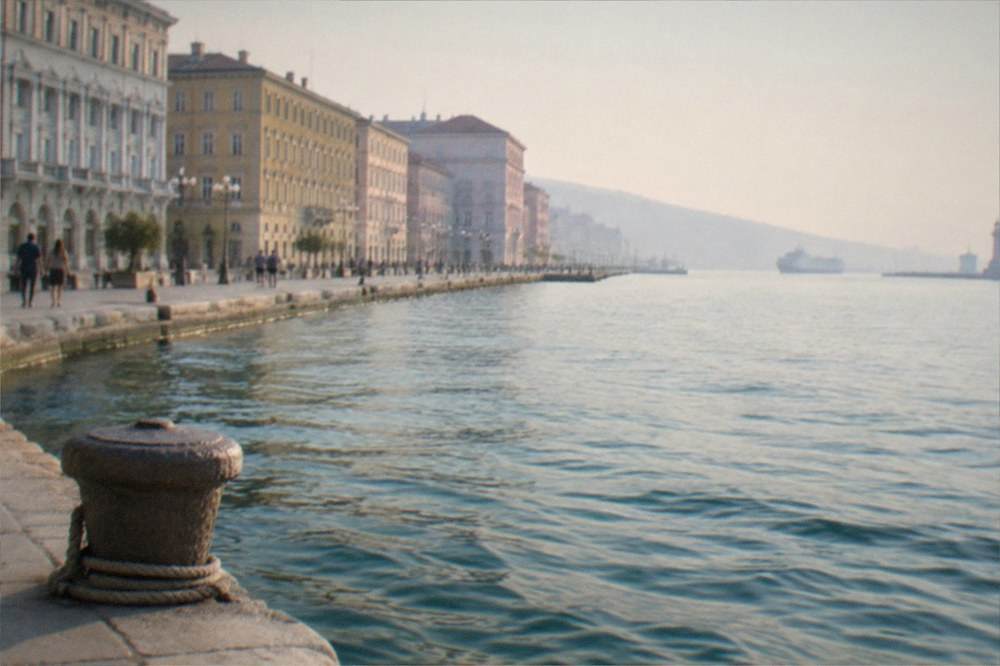 A wide Italian seaside square with grand facades facing open water at dusk