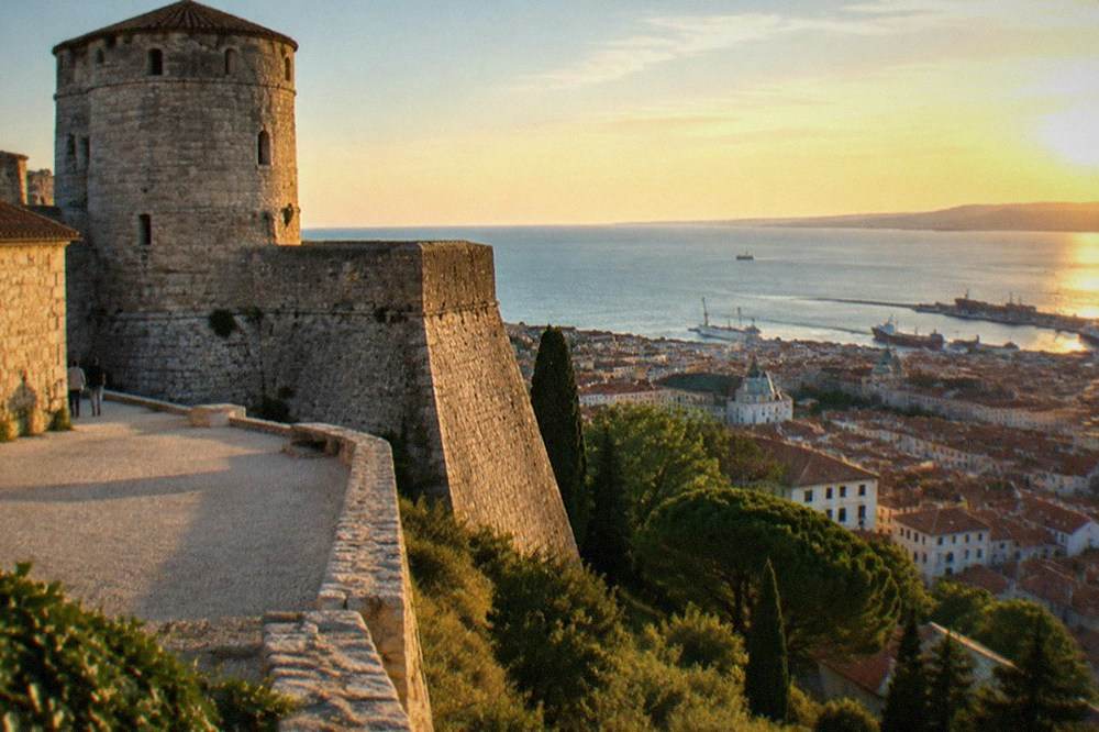 The stone walls and round tower of Castello di San Giusto above Trieste's rooftops