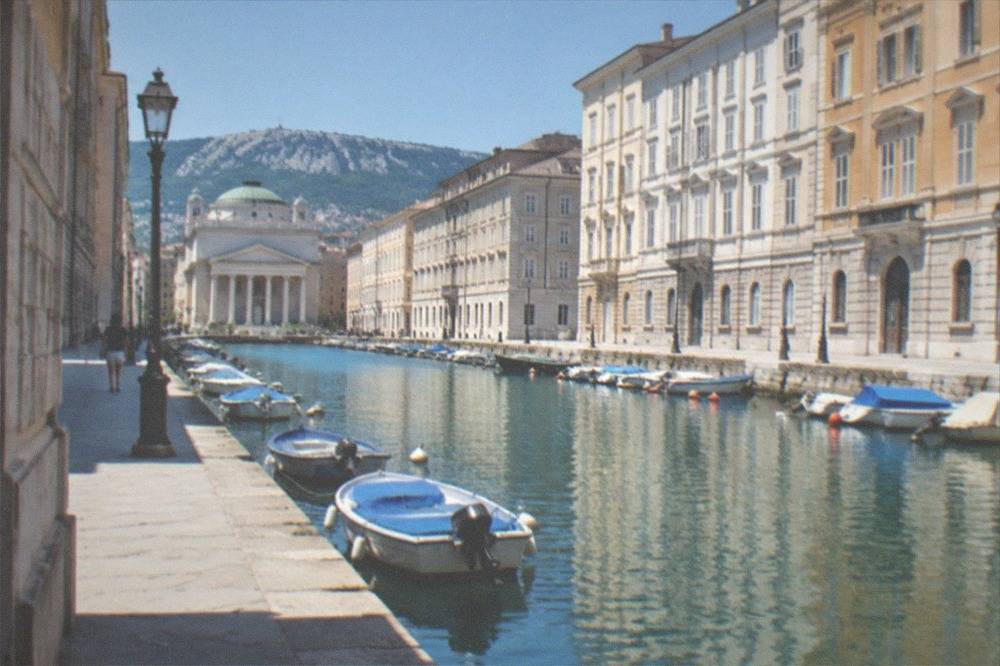 Neoclassical buildings along a canal in Trieste with a church at the end