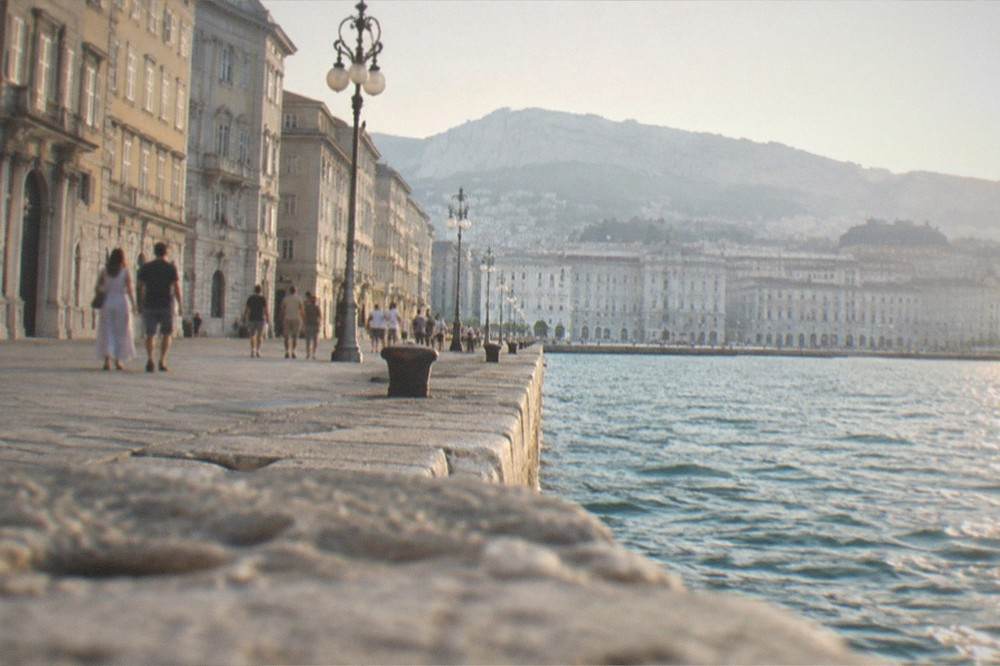 Evening lights along a waterfront with people strolling beside the water
