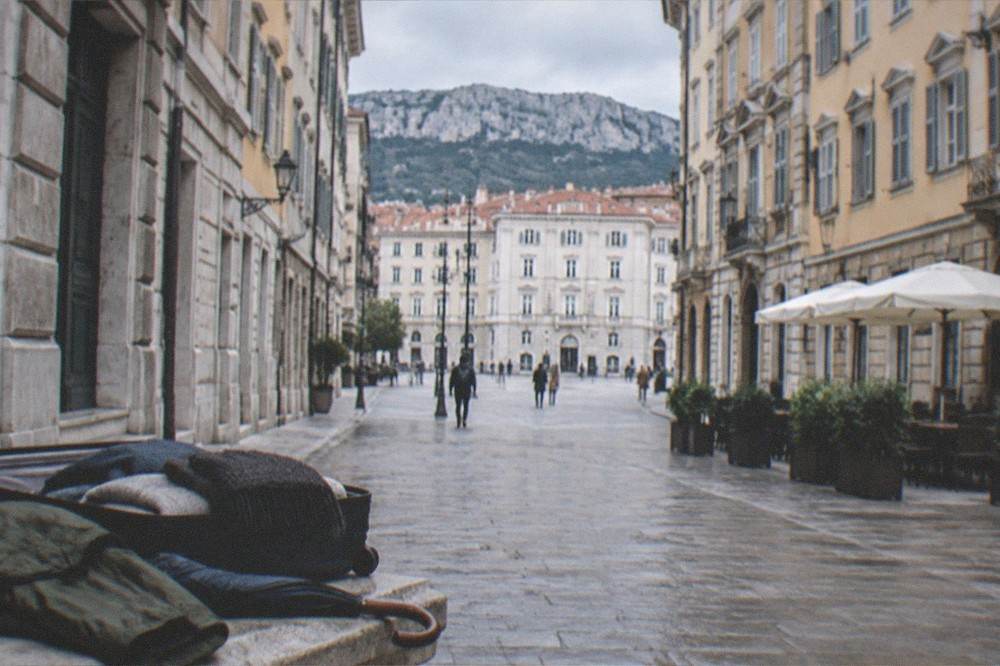 A packed suitcase with a rain jacket, umbrella and warm scarf laid out for a trip