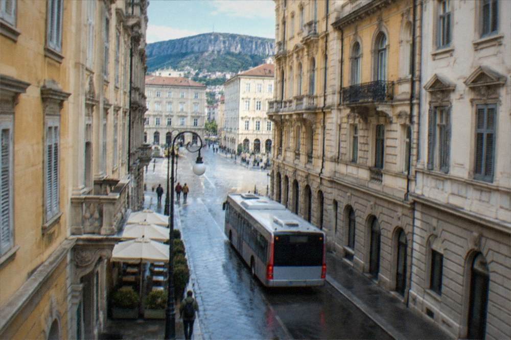 A city bus passing ornate nineteenth century buildings on a Trieste street