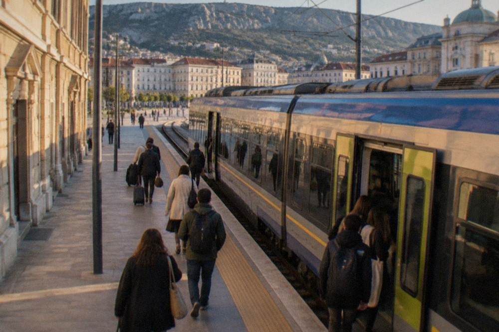 A regional train waiting at a platform in an Italian railway station with passengers boarding
