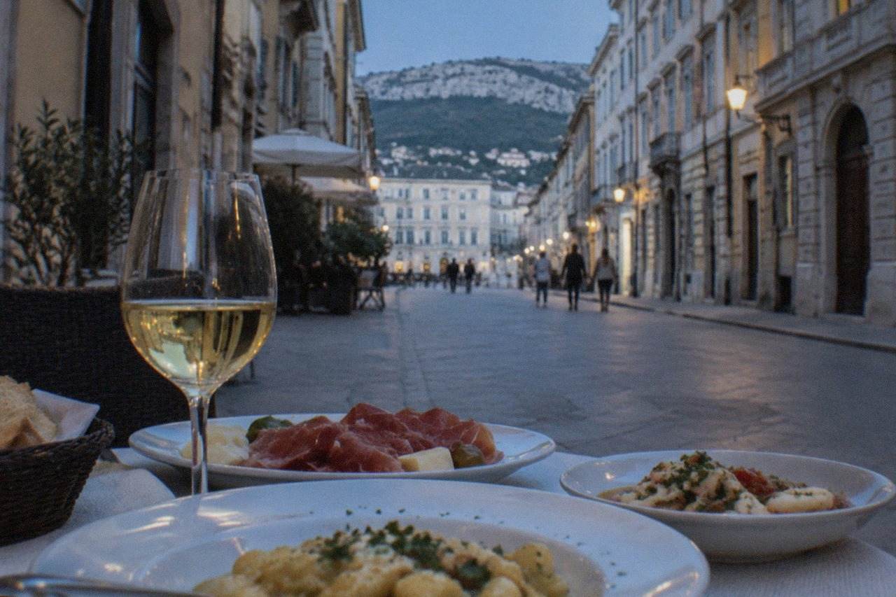 A table of regional dishes and a glass of local wine at a Trieste restaurant