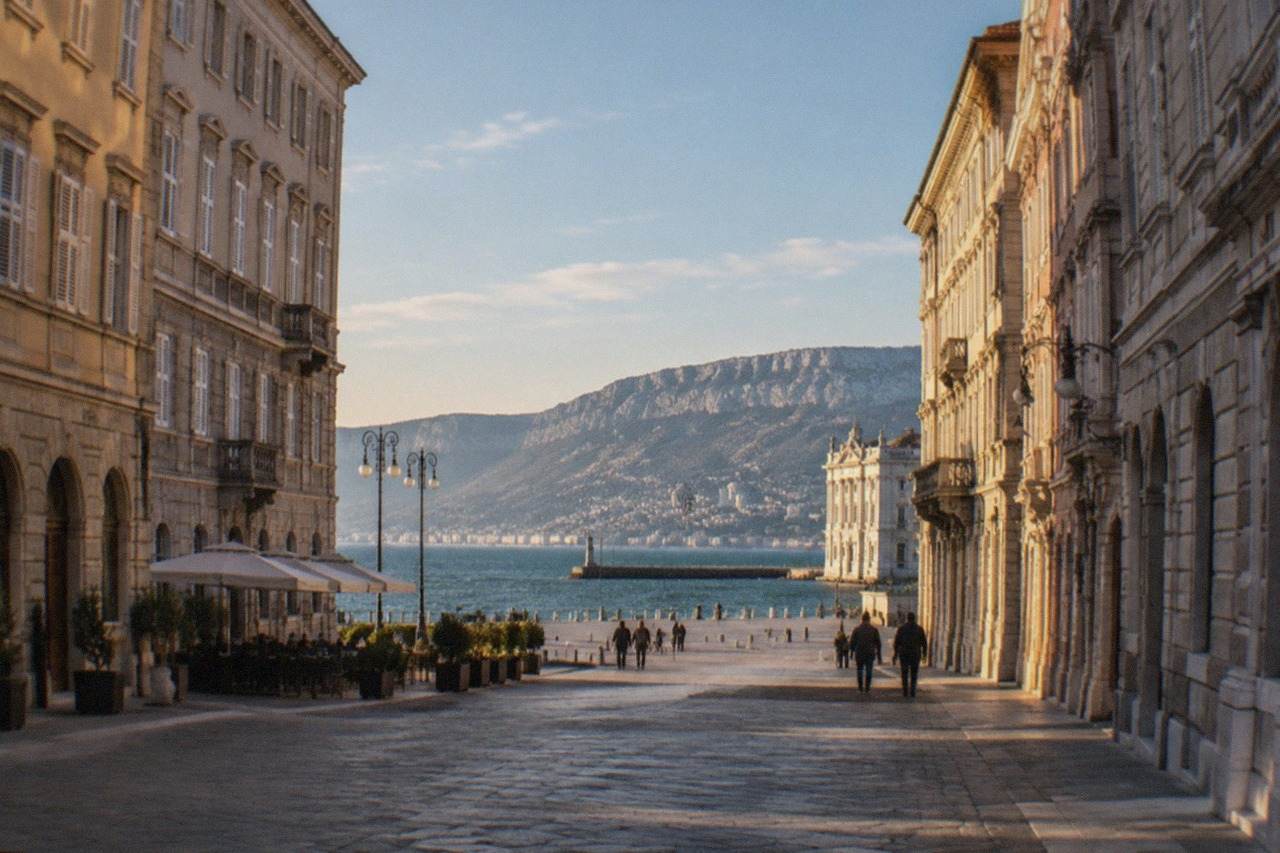 Elegant Habsburg-era buildings along a wide street in Trieste with the sea in the distance