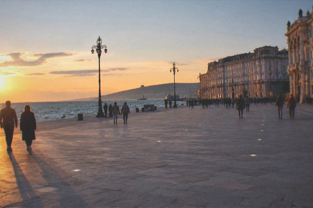 Evening light on Piazza Unità d'Italia in Trieste with people walking by the seafront