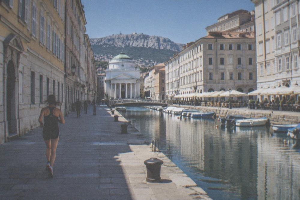 A straight urban canal with a church at its head and cafés along the banks