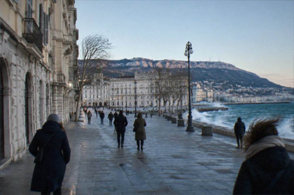 Wind-blown flags and clear sky over the Trieste seafront in winter light