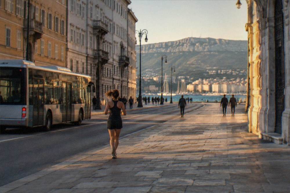 A city bus and passengers on a street in central Trieste near the seafront