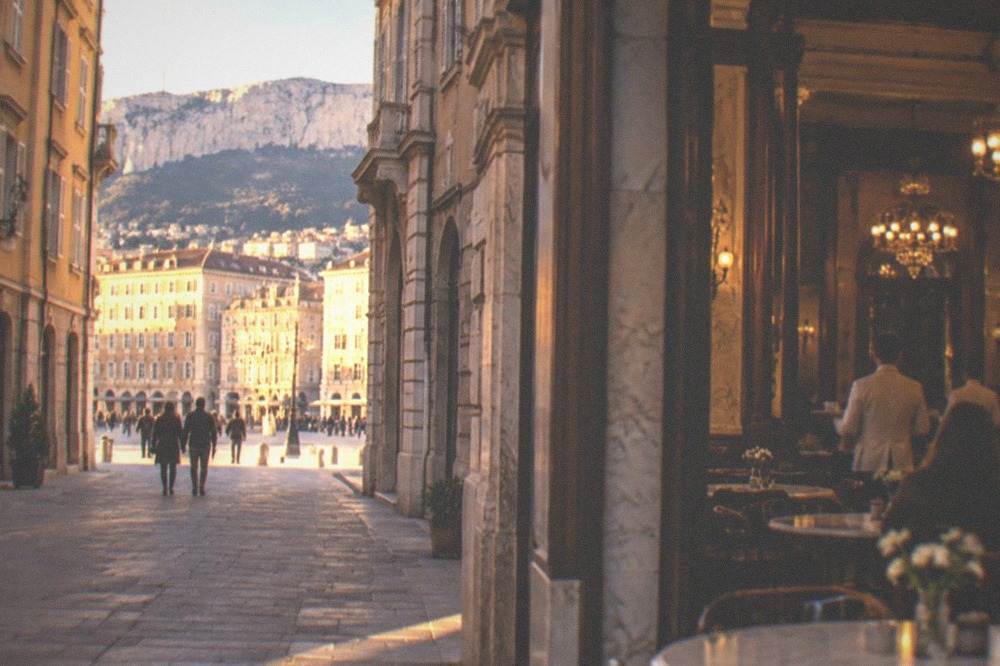 A historic cafe interior in Trieste with marble tables, chandeliers and waiters in white jackets