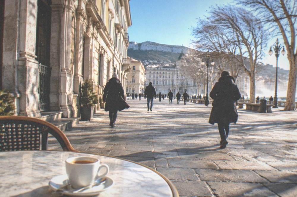 A marble-topped table in an ornate Trieste coffee house with a small cup of espresso