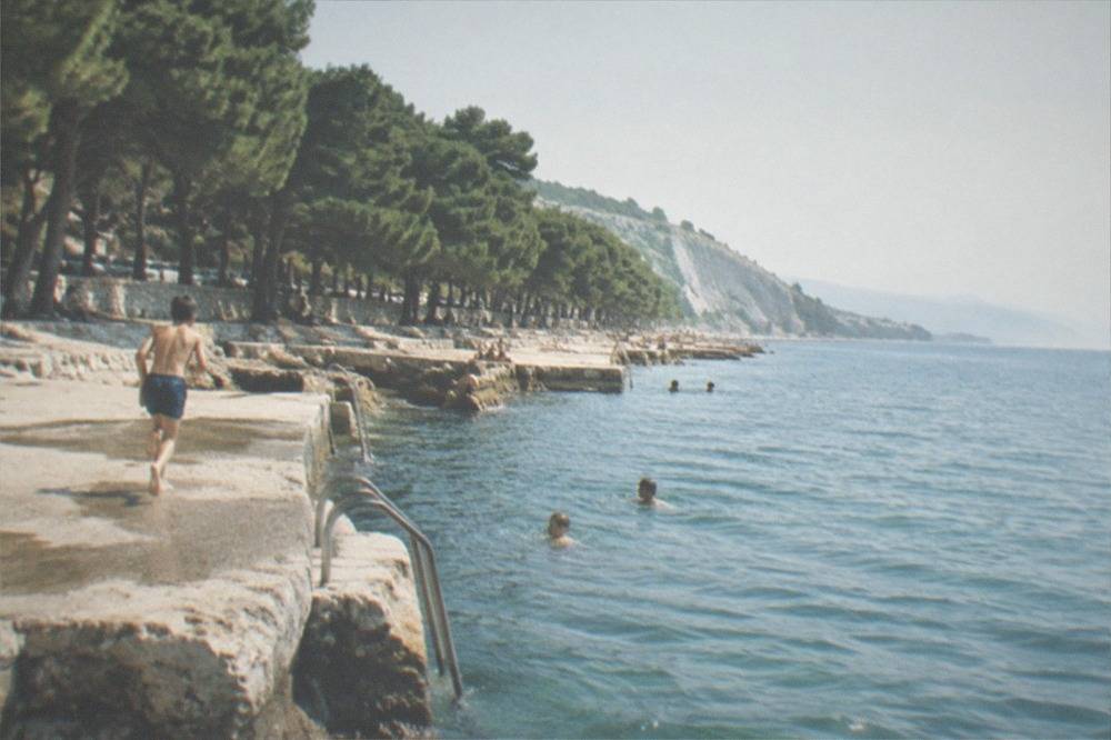 Children swimming from the rocks at the Barcola seafront on a summer afternoon