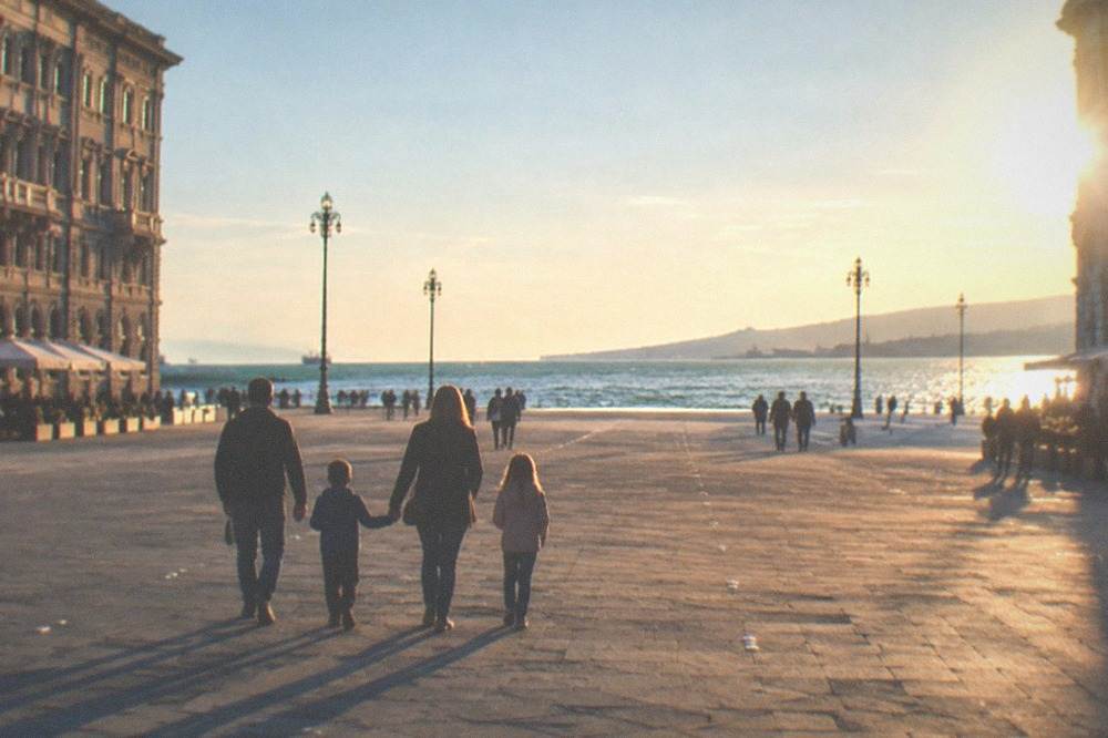 A family crossing Piazza Unità d'Italia toward the sea