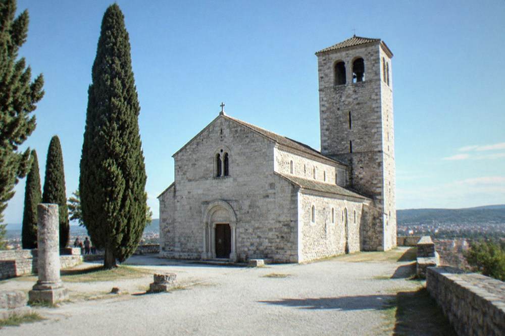 The white limestone facade of Trieste Cathedral beside the castle ramparts on San Giusto hill