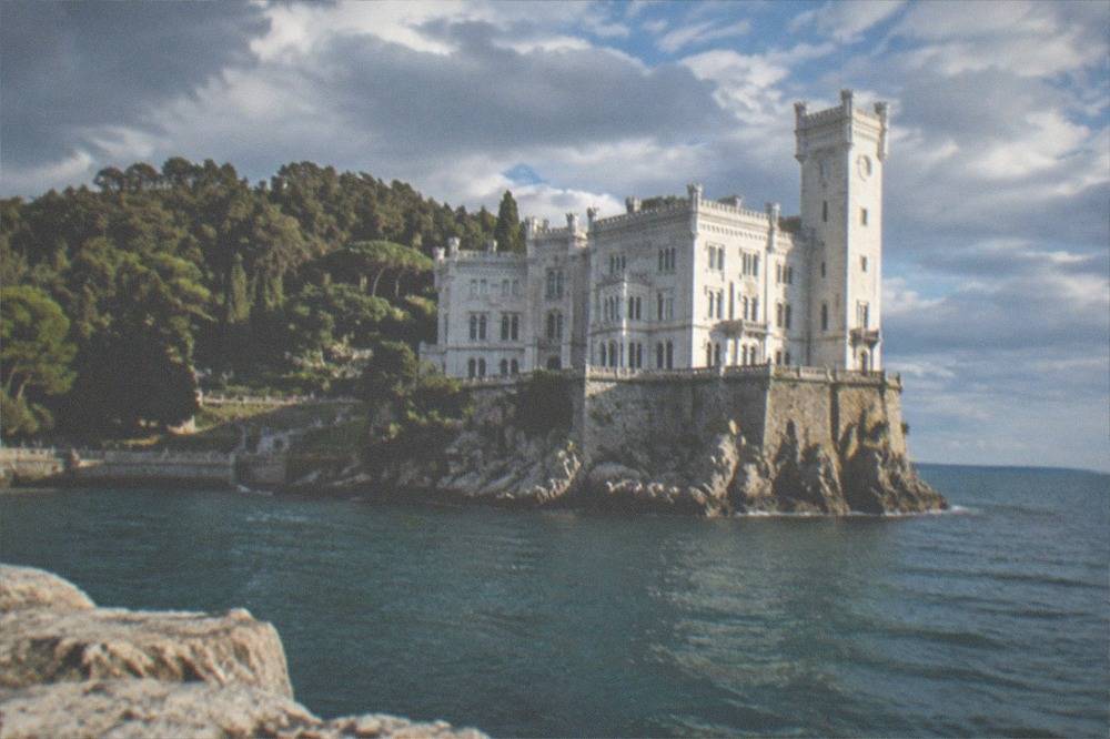 The white turreted Miramare Castle standing above the Adriatic with its wooded park on the headland